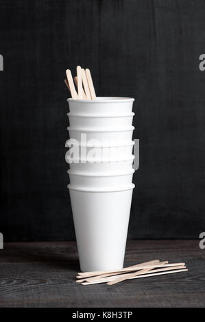Steck of disposable cups with wooden sticks on the dark brown table Stock Photo
