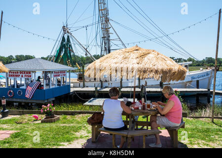 North Carolina,NC,Calabash,fishing town,seafood,regional cuisine,dining,al fresco sidewalk outside outdoors tables,straw umbrella,fishing boat,dock,Ca Stock Photo