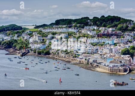 A colourful summer picture taken from a long distance of old Fowey Town and Quay close to Regatta Week with picturesque moored boats in the estuary. Stock Photo