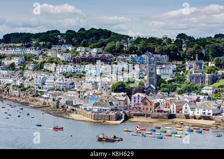 A colourful summer picture taken from a long distance of old Fowey Town and Quay close to Regatta Week with picturesque moored boats in the estuary. Stock Photo