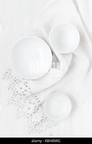 Empty white plates on  the light wooden table with vintage towel Stock Photo