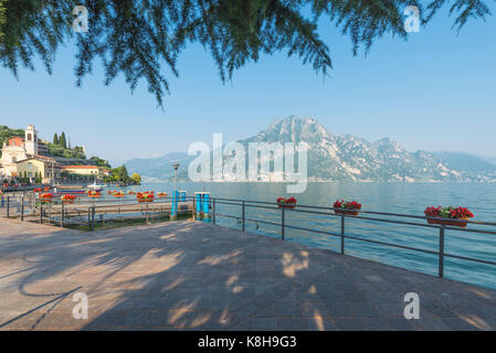 View from the lakeside at central square in medieval Riva di Solto on mountains in the evening sun at Lake Iseo, Lombardy, Italy Stock Photo