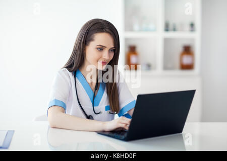 Confident beautiful doctor working on laptop in hospital Stock Photo