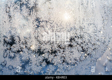 wintry frosty pattern on glass. abstract background of ice frozen window. winter day, sun shine through frosted glass on window. Stock Photo