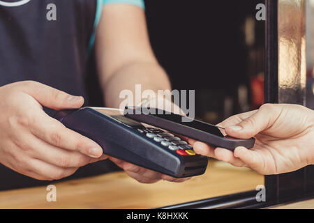 Person paying pay through smartphone using NFC Stock Photo