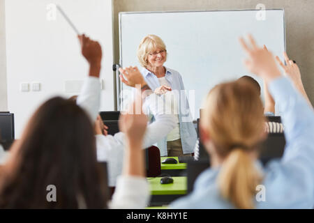 Many students in school lessons raising hands Stock Photo