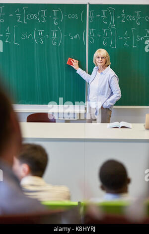 Math teacher in class with chalkboard in university or college Stock Photo