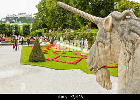 Salzburg, Austria - July 4, 2013: Unicorn statue facing beautiful Mirabell Gardens with walking visitors, a castle Hohensalzburg is seen on the backgr Stock Photo