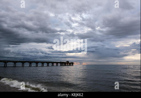 storm clouds rolling in over an ocean fishing pier at sunrise Stock Photo
