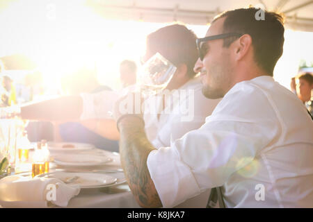 Outdoor shot of handsome young man drinking wine at a summer party with a friend Stock Photo