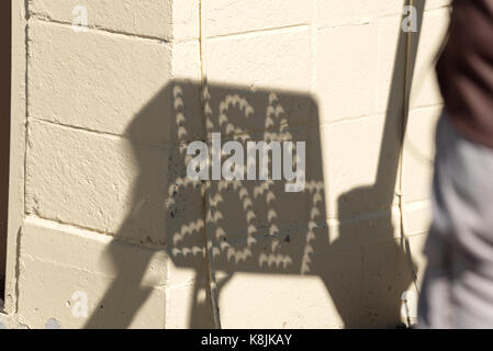 Eclipsing sun shadows cast on building through USA 2017 sign, Oregon. Stock Photo