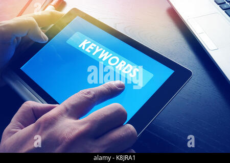 Word Keywords on a tablet as a part of SEO. Stock Photo
