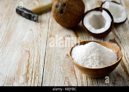 Grated coconut in bowl with its shell on background Stock Photo