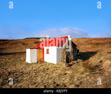 A brightly painted crofters cottage brings a splash of colour to remote moorlands on the Isle of Skye in the Scottish Highlands Stock Photo