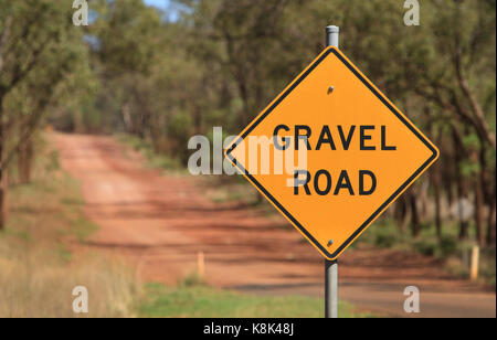 Gravel Road road sign in rural Queensland with track leading through Australian bush landscape Stock Photo