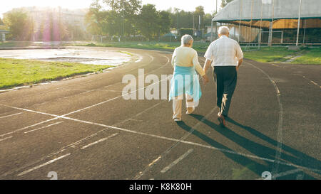Senior couple walking along the running track Stock Photo
