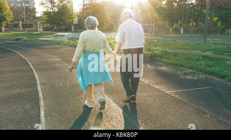 Senior couple walking along the running track Stock Photo