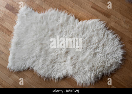 Photo of a Sheepskin wool rug on a wooden floor Stock Photo