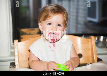Happy messy baby with food on her face after eating dessert Stock Photo
