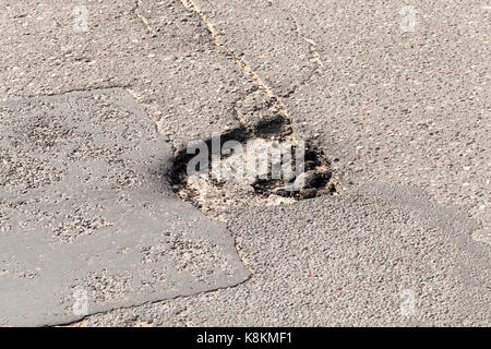 Broken asphalt. Picture of a road with large holes close up. Repair of the old road with poor quality of the road surface Stock Photo
