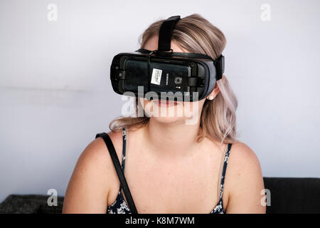 Teenager girl wearing Oculus Gear VR headset, virtual reality (VR) equipment with Samsung phone. Stock Photo