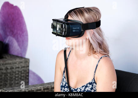 Teenager girl wearing Oculus Gear VR headset, virtual reality (VR) equipment with Samsung phone. Stock Photo