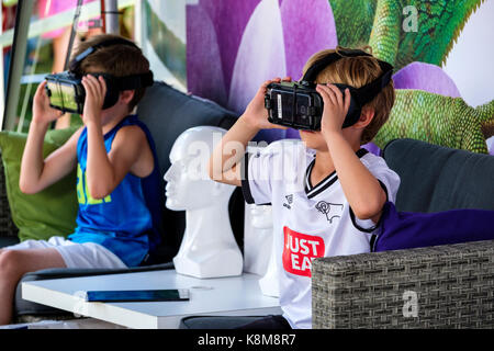 Young boys wearing Oculus Gear VR headset, metaverse virtual reality (VR) equipment with Samsung phone at a Telus Mobility booth. Stock Photo