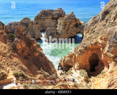 LAGOS, PORTUGAL - JULY 05, 2017: Tourists hiking the trail in summer between the ridge of the rocks and the sea level in Ponta da Piedale, Algarve are Stock Photo