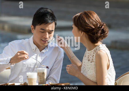 Prague, Czech Republic - August 19, 2017: Couple of lovers play with dirty cappuccino cream saucers sitting at a cafe`s table Stock Photo