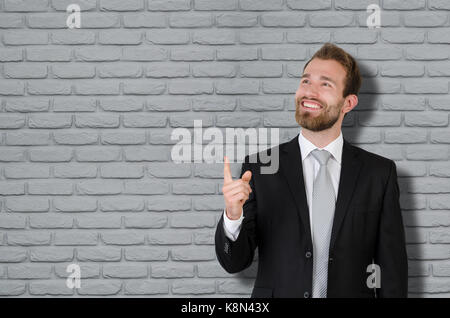 Handsome elegant businessman in suit copy space, showing up, pointing finger concept Stock Photo