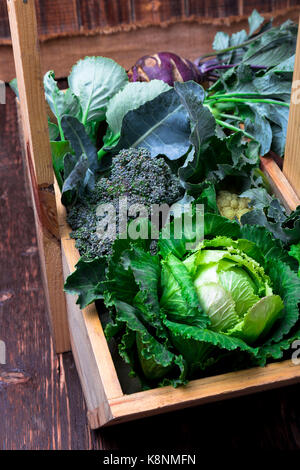 Variety of cabbages in wooden basket on brown background. Harvest. Close up Stock Photo
