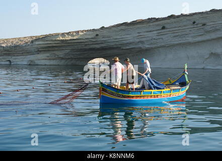 Fishing from a traditional colourful luzzu boat, Il-Hofra I-Kbira bay, Malta Stock Photo