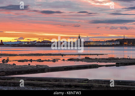 A beautiful  sunset over Ardrossan and Arran with the firey sun reflecting off the water on the bay between Saltcoats and Ardrtossan. Stock Photo