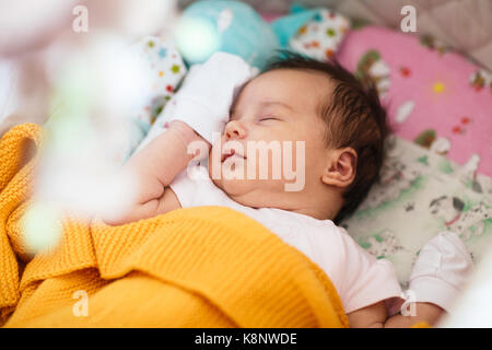 Sweet newborn baby girl is sleeping in her crib. Stock Photo
