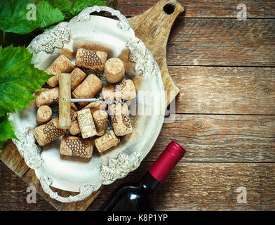 Grapes,a bottle of wine, corks and corkscrew on a wooden old table, rustic style. Stock Photo