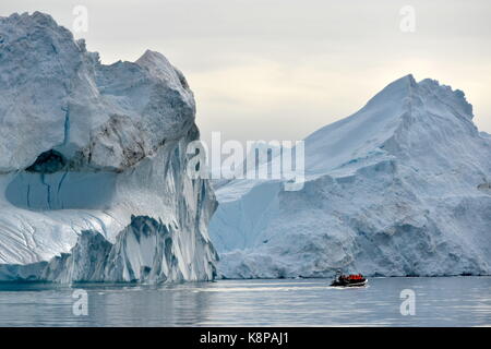 A fishing boat with tourists makes its way through icebergs floating in the fjord near Ilulissat on the west coast of Greenland. The icebergs can reach 100 metres above water level and are formed around 65 kilometres away on the Kangia glacier. This is how 40 million tonnes of ice make their way to the fjord, which has been classed as a UNESCO world natural heritage site since 2004. Taken 22.08.2017. Photo: Karlheinz Schindler/dpa-Zentralbild/ZB | usage worldwide Stock Photo