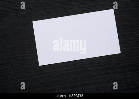 Photo of blank white business cards on a dark wooden background. Mock-up for branding identity. Stock Photo