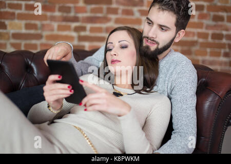 Young couple online shopping by digital tablet, lying on sofa indoor Stock Photo