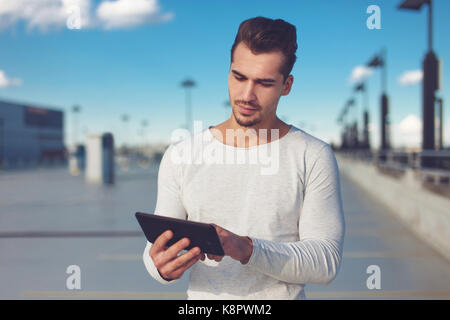Young casual man using digital tablet outdoor, large space Stock Photo
