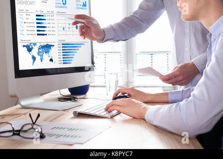 Team of financial people discussing a business analytics (BA) or intelligence (BI) dashboard on the computer screen showing sales and operations data  Stock Photo