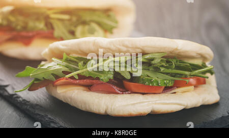 rustic sandwiches with ham arugula and tomatoes in pita bread, on wood table Stock Photo