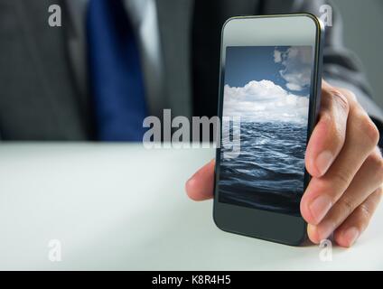 Digital composite of Hand holding phone with sea Stock Photo