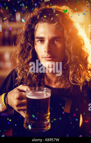 Flying colours against portrait of young man holding drink Stock Photo