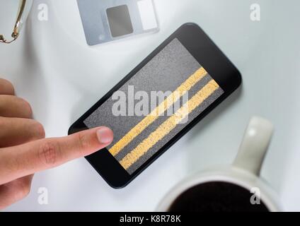 Digital composite of Hand touching phone with road Stock Photo