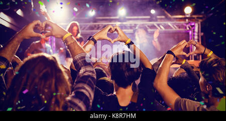 Flying colours against crowd making heart shape with hands during performance Stock Photo