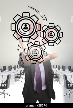 Digital composite of Business man interacting with people in cogs graphics against office background Stock Photo