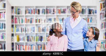 Smiling teacher with students  against teacher reading books to her students Stock Photo