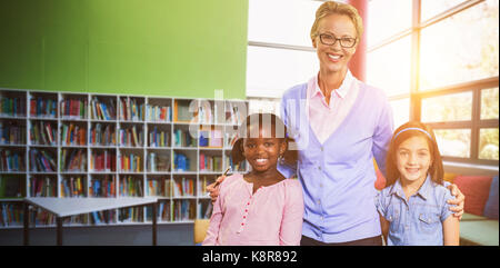 Portrait of happy teacher with students against school library Stock Photo