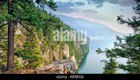 Trees growing on mountain by river against sky Stock Photo