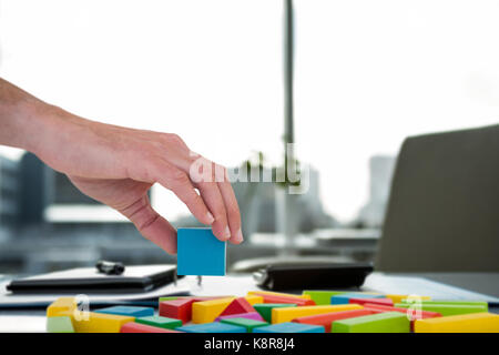 Cropped hand arranging colorful blocks against documents are posing on the desk Stock Photo